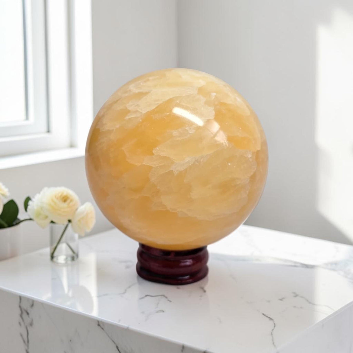 Yellow calcite sphere on dark wooden stand, glossy surface with natural striations