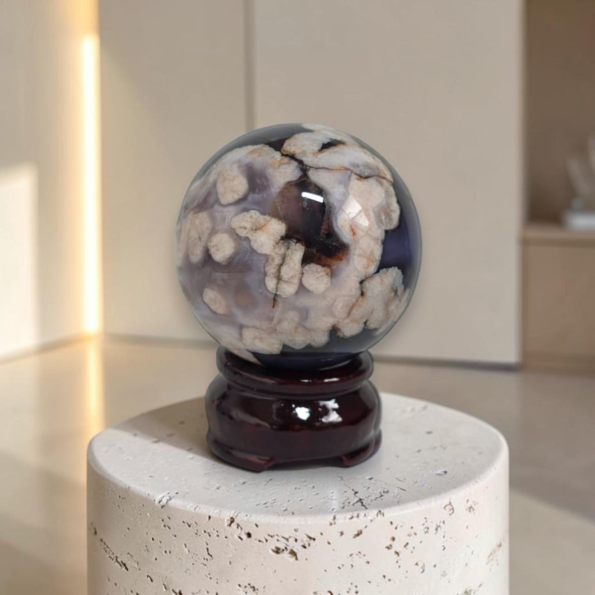 Polished blue agate sphere on dark wood stand, marbled cream inclusions.