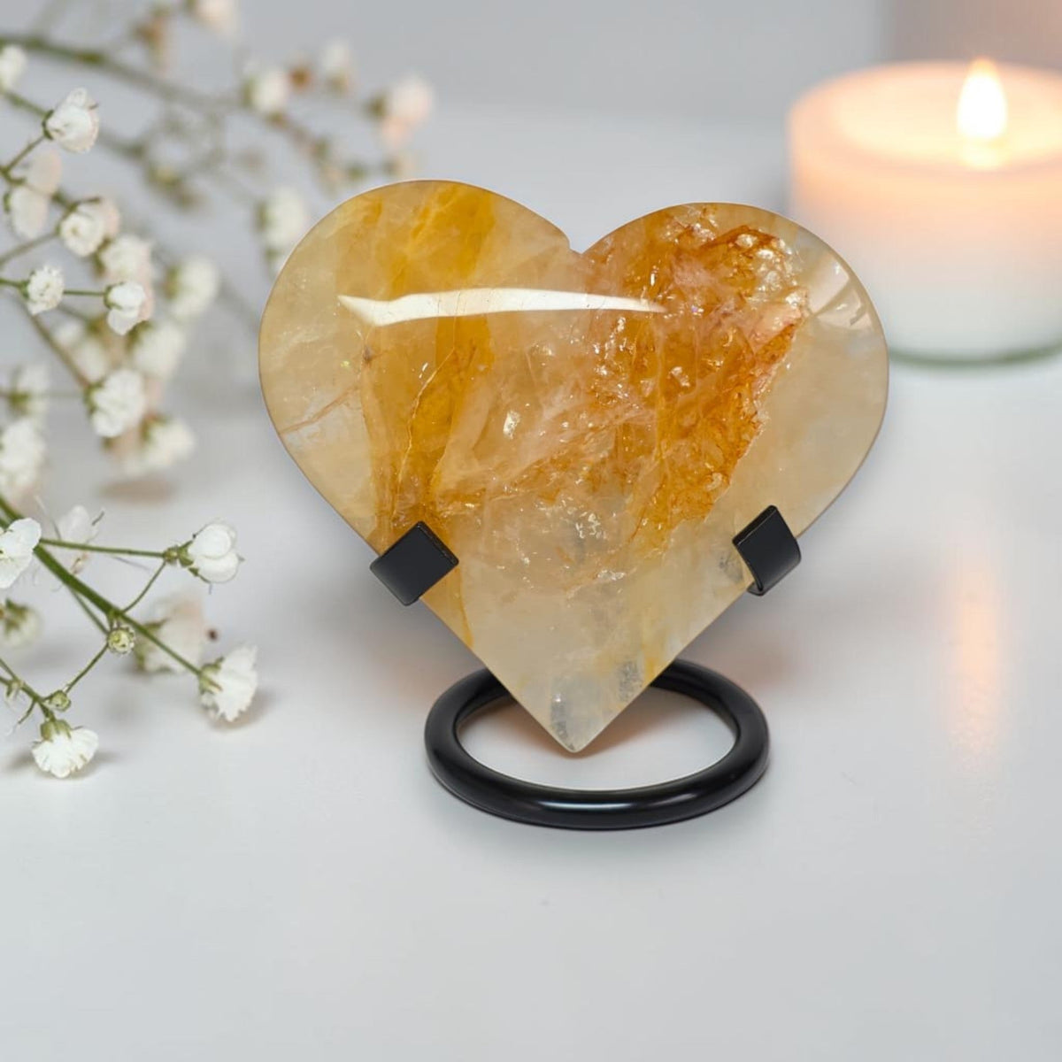 Polished golden quartz heart crystal on black stand, translucent with orange veining
