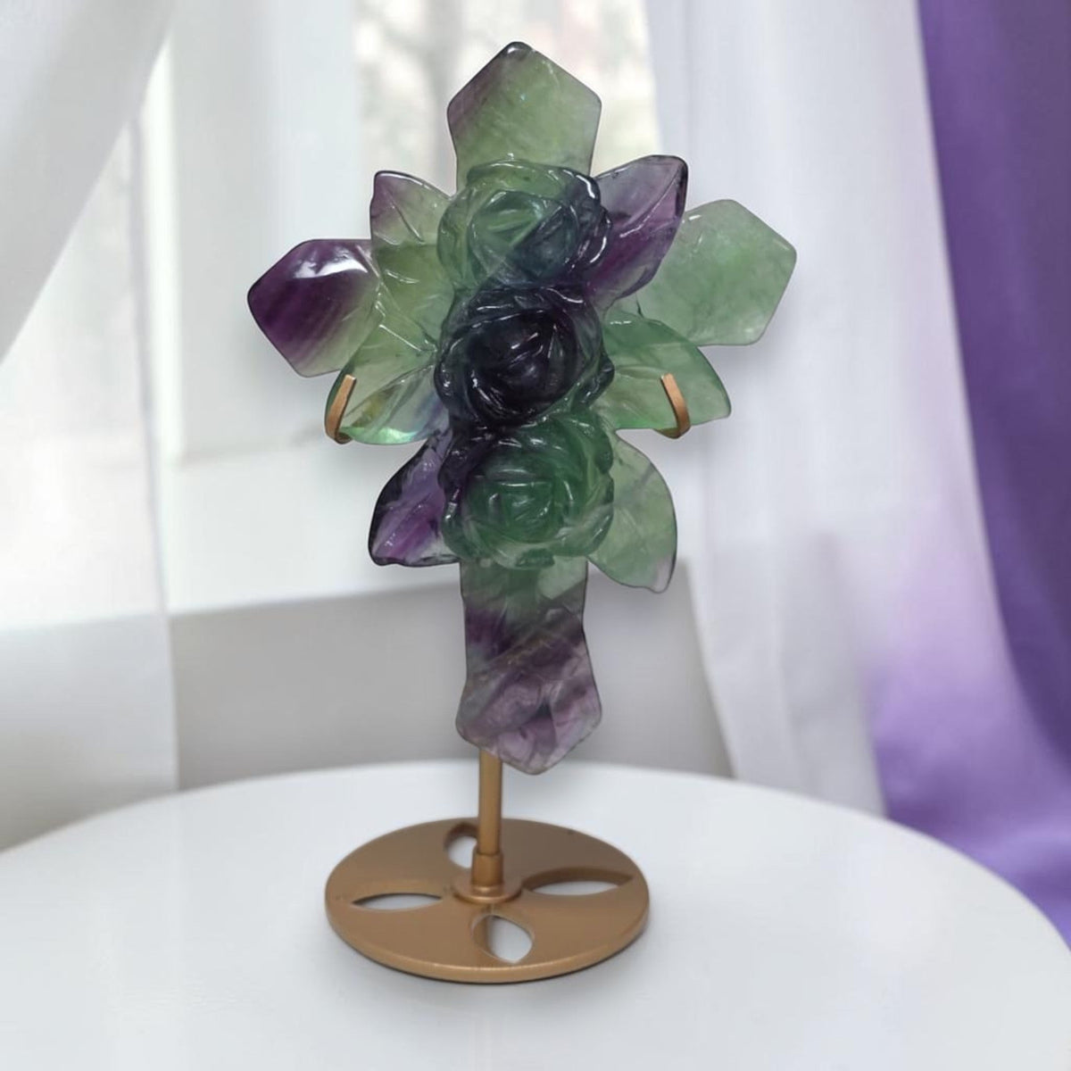 Rainbow fluorite cross sculpture with carved rose details on metal stand, front view