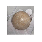 Honey calcite crystal sphere resting on light gray fabric, pale honey-gold finish