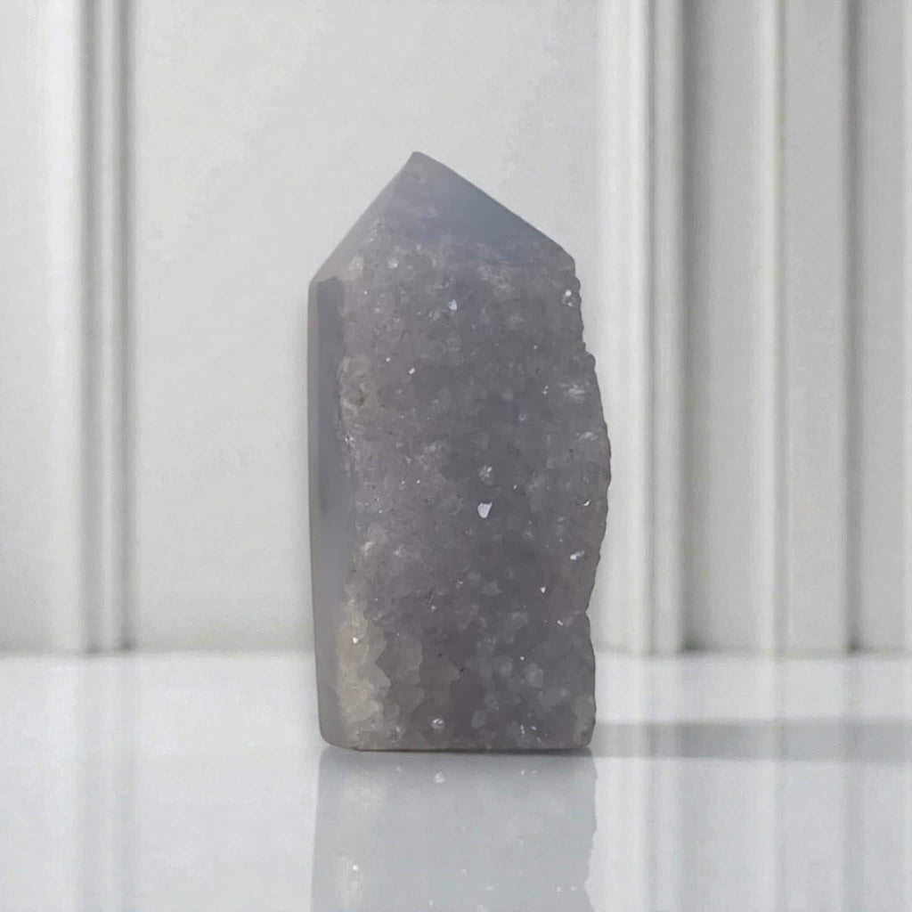 Purple-blue druzy crystal tower with a pointed top and dense sparkling surface