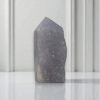 Purple-blue druzy crystal tower with a pointed top and dense sparkling surface