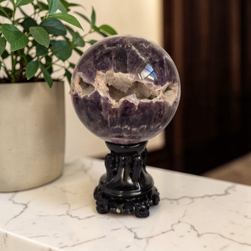 Purple amethyst drusy sphere with geode-like texture on black pedestal stand