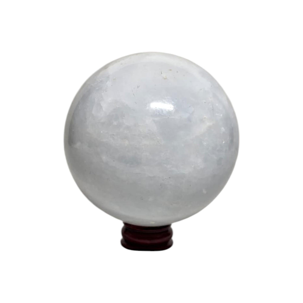 White-gray calcite crystal ball sphere, glossy surface, on dark wooden stand