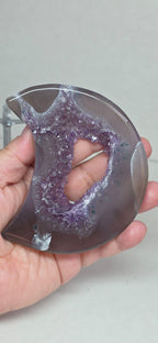 Purple drusy geode crescent moon on metal stand, close-up in hands
