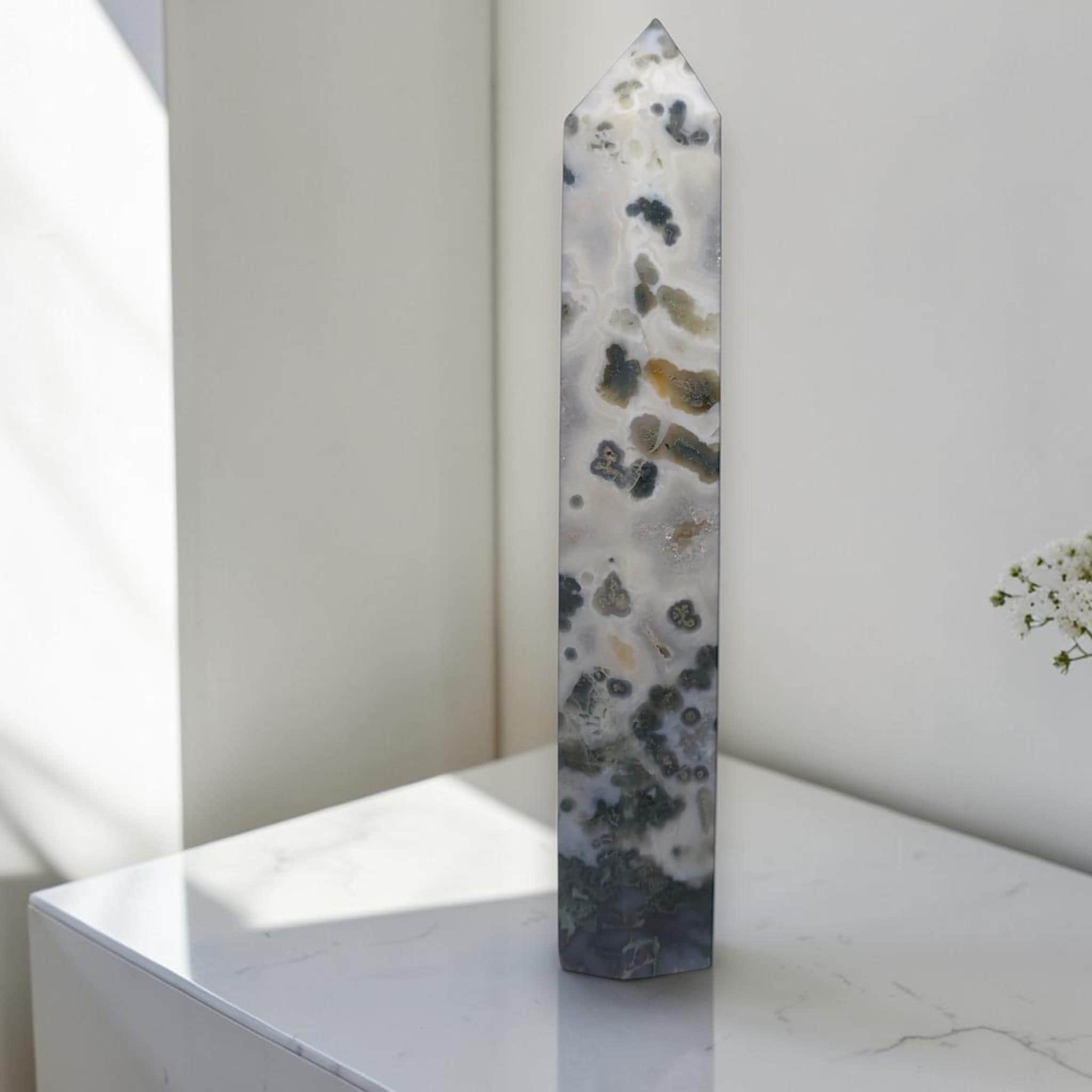 Natural crystal obelisk with translucent white body and mottled dark green patterns, point