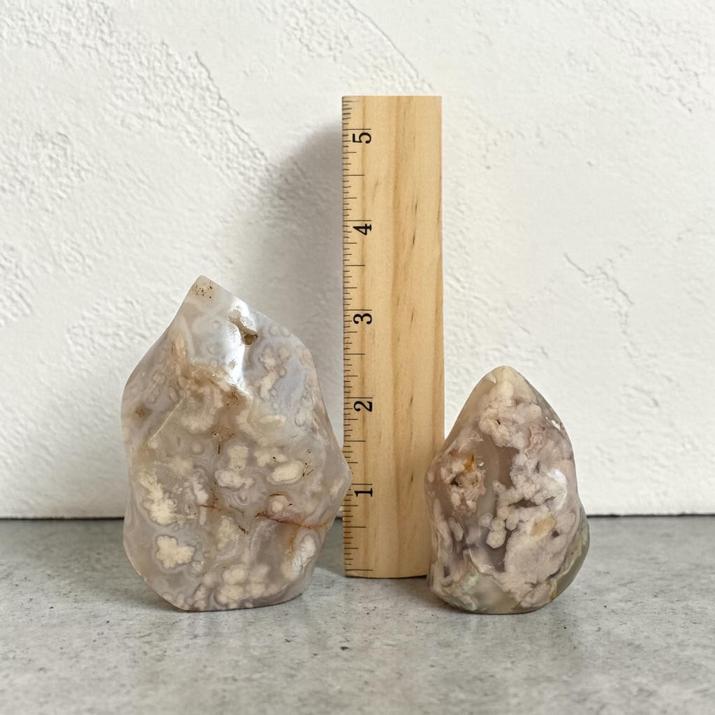Agate flame crystals beside a wooden ruler: large and small, clear beige with white inclusions