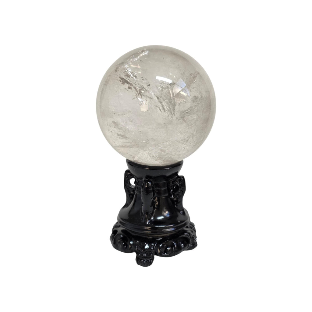 Polished clear quartz sphere on black ornate base, glossy crystal with sparkly reflections