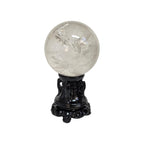 Polished clear quartz sphere on black ornate base, glossy crystal with sparkly reflections
