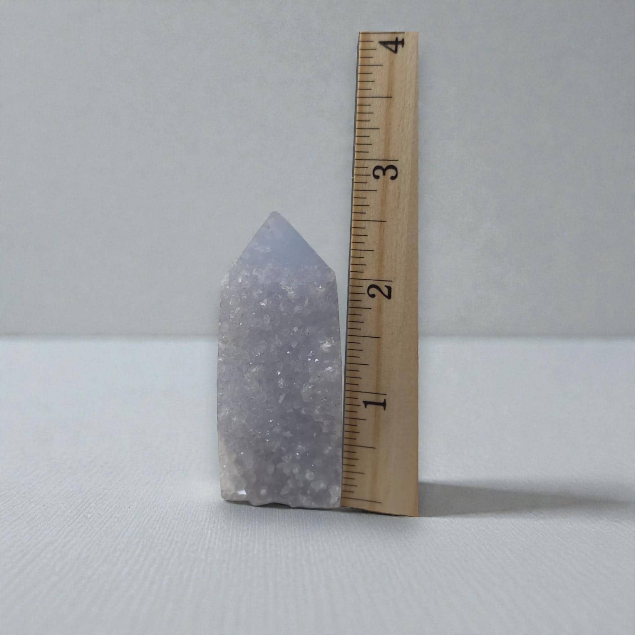 Light blue druzy agate obelisk beside a wooden ruler for size reference