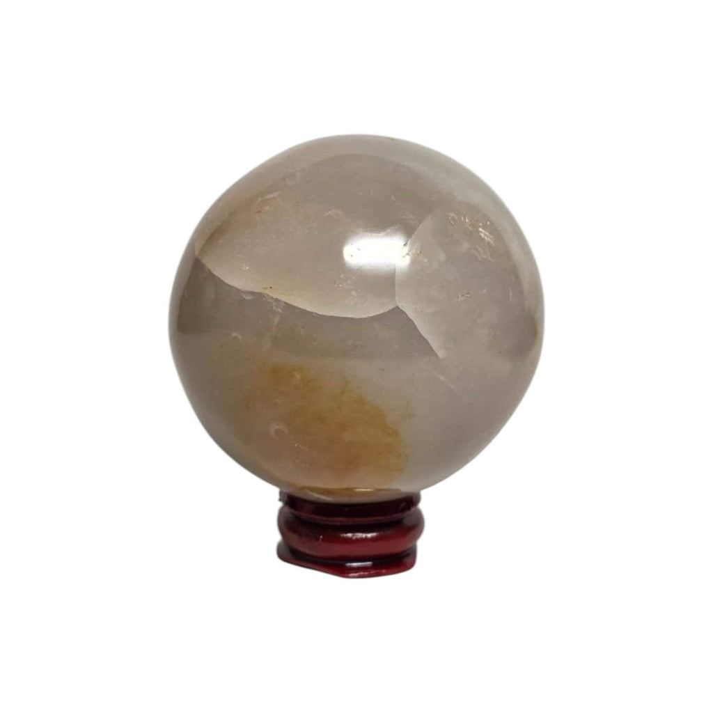 Honey calcite crystal sphere on dark red stand, translucent gray-beige with cloudy texture