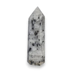 Tourmalinated quartz obelisk with scattered black inclusions inside translucent crystal.
