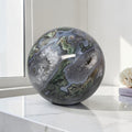 Moss agate geode sphere: dark gray-blue with green mossy patches and clear druzy quartz