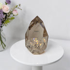 Smoky quartz crystal on gold stand, faceted clear stone with rainbow iridescent flecks
