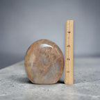 Large polished peach moonstone crystal, rounded dome next to measuring ruler