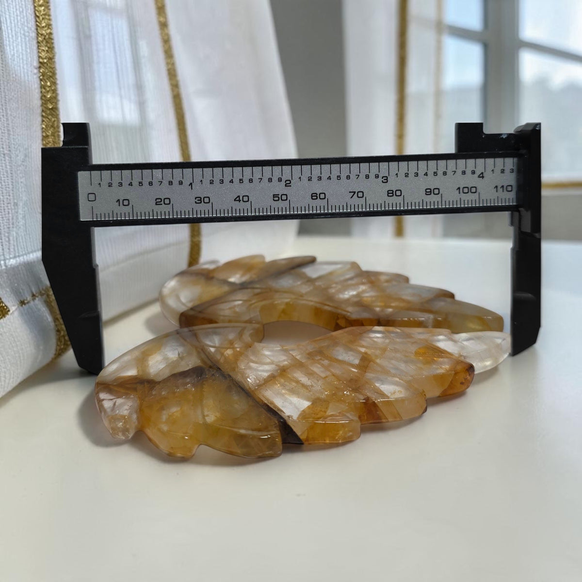 Golden Healer quartz wings beside a width measuring gauge