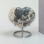 Heart-shaped stone on a metal stand against a light background