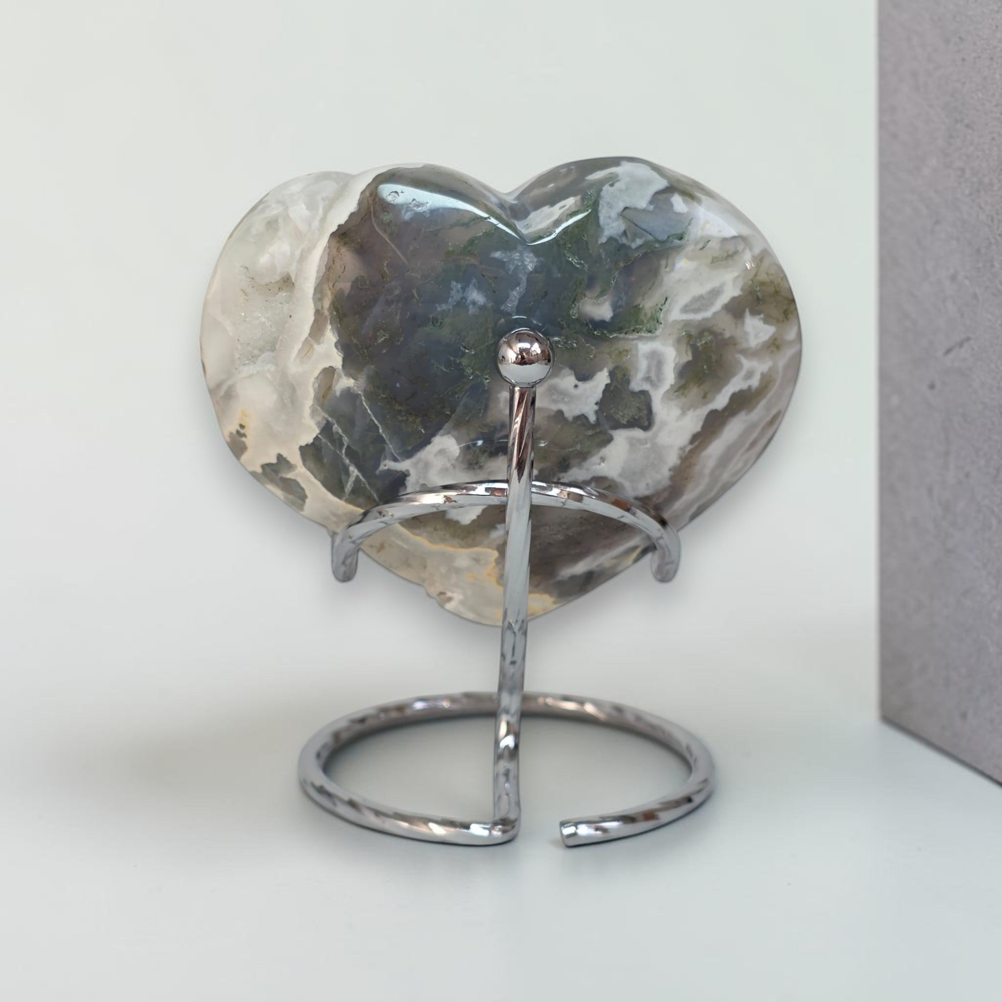 Heart-shaped stone on a metal stand against a light background