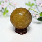 Golden Healer Quartz sphere on wood stand with floral background