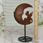 Banded agate moon fairy sculpture on stand, side view with pink cherry blossoms