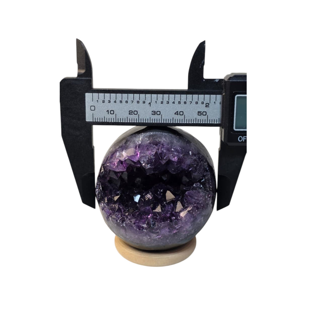 Amethyst geode crystal sphere with caliper gauge, dark purple and black crystal interior
