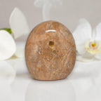 Polished peach moonstone crystal, rounded oblong with small dark spot and web-like striations