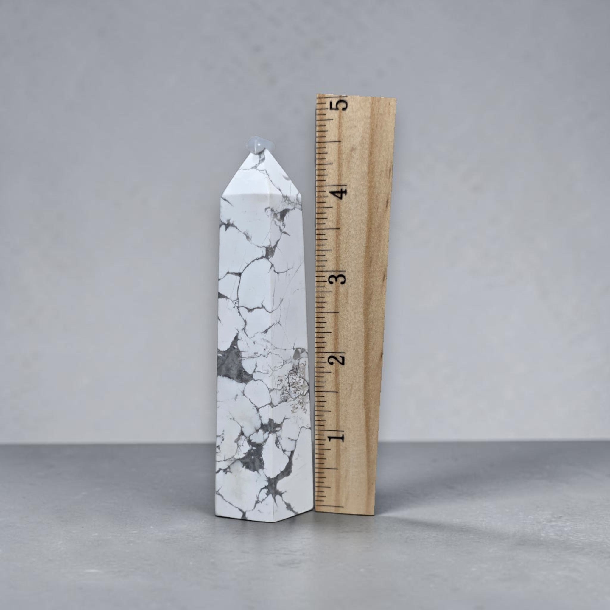 White howlite tower next to measuring tape, pointed tip