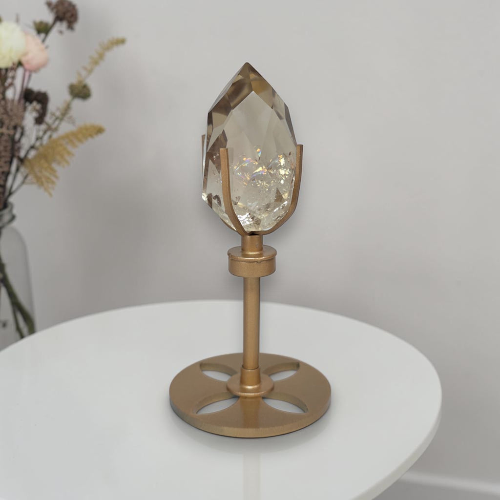 Smoky quartz crystal on rotating gold pedestal stand with faceted smoky-clear top