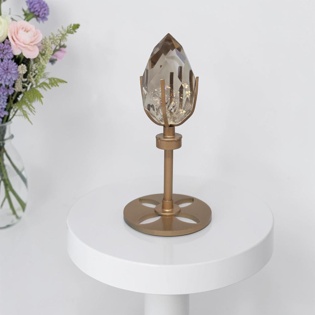 Smoky quartz crystal centerpiece on rotating gold base stand, clear smoky faceted top