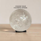 Polished clear quartz sphere gemstone on black display stand, glossy reflective surface