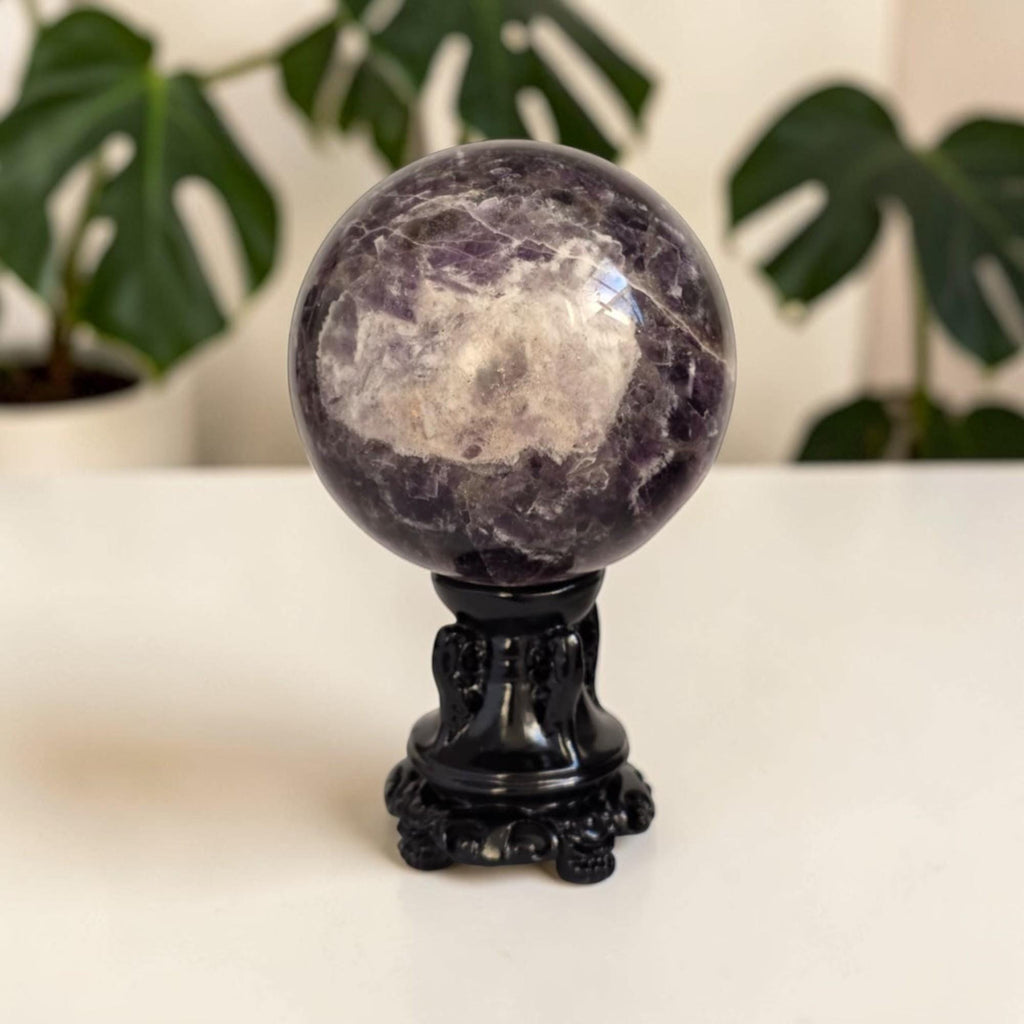 Purple amethyst druzy sphere with pale quartz bands, on black stand