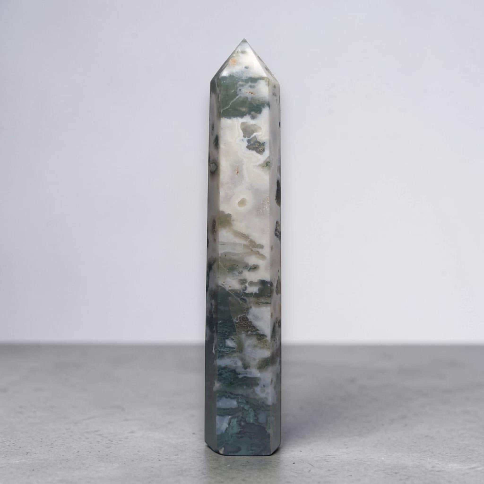 Natural crystal obelisk with blue-green base and dark speckled bands, pointed top