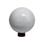 Translucent calcite sphere with glossy finish on dark wooden stand, close view