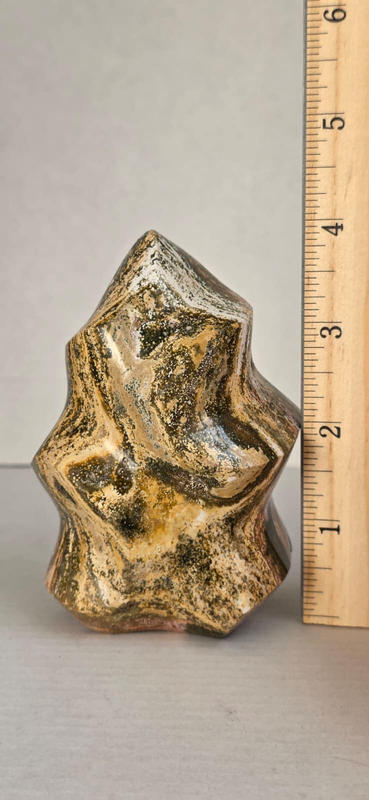 Ocean jasper flame crystal specimen beside ruler, gold and dark speckled pointed freeform.