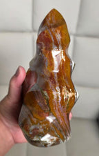 Polished flame-shaped jasper crystal, reddish-brown and amber streaks with bright shine