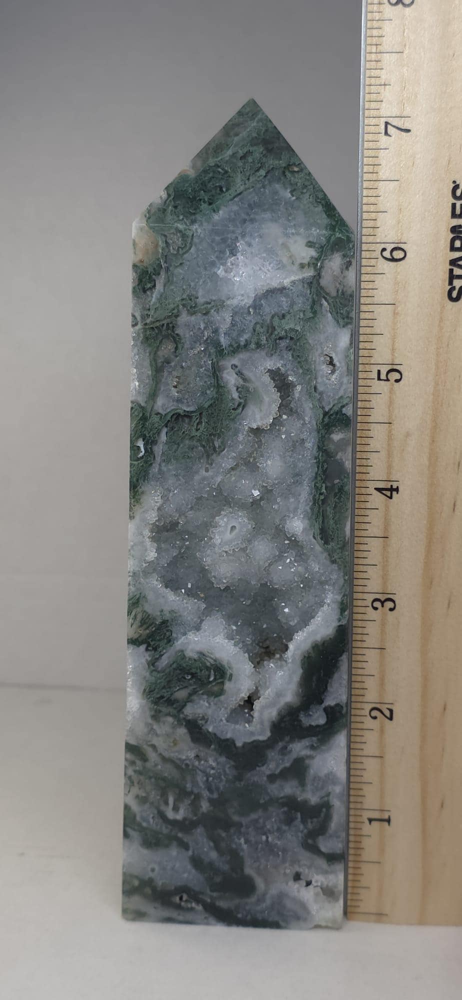 Moss agate obelisk with pointed top beside measuring ruler; green, gray and white bands