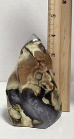 Polished agate stone decor next to ruler, yellow-brown and dark gray patterned finish