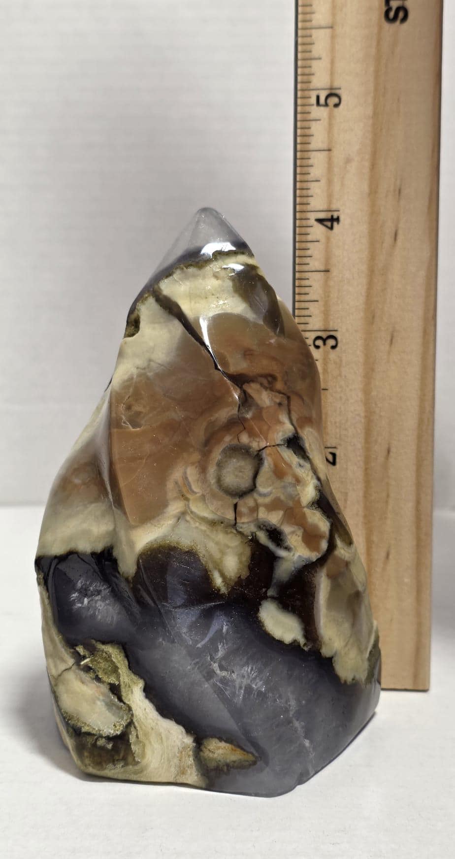 Polished agate stone decor next to ruler, yellow-brown and dark gray patterned finish
