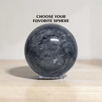 Dark gray jasper crystal ball sphere with natural stone veining on clear display stand