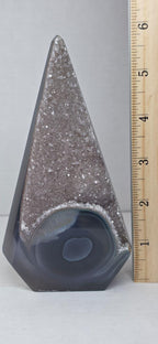 Druzy agate obelisk tower next to a wooden ruler; purple glitter top, dark banded base