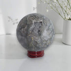 Grey agate geode sphere on red stand, blue-gray quartz and mottled mineral patterns