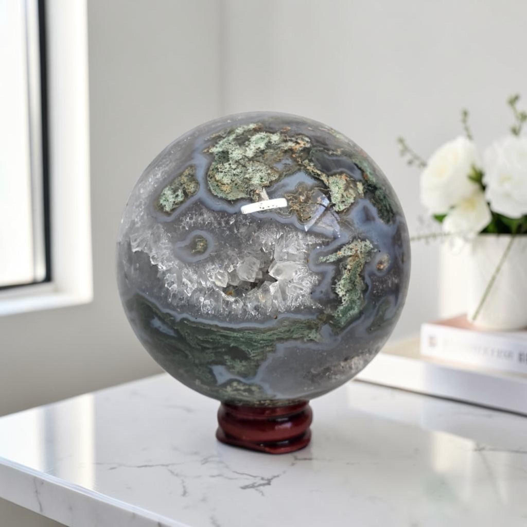 Moss agate geode sphere: dark gray-blue with bright green mossy areas and white druzy quartz