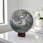 Moss agate geode sphere: dark gray-blue with bright green mossy areas and white druzy quartz