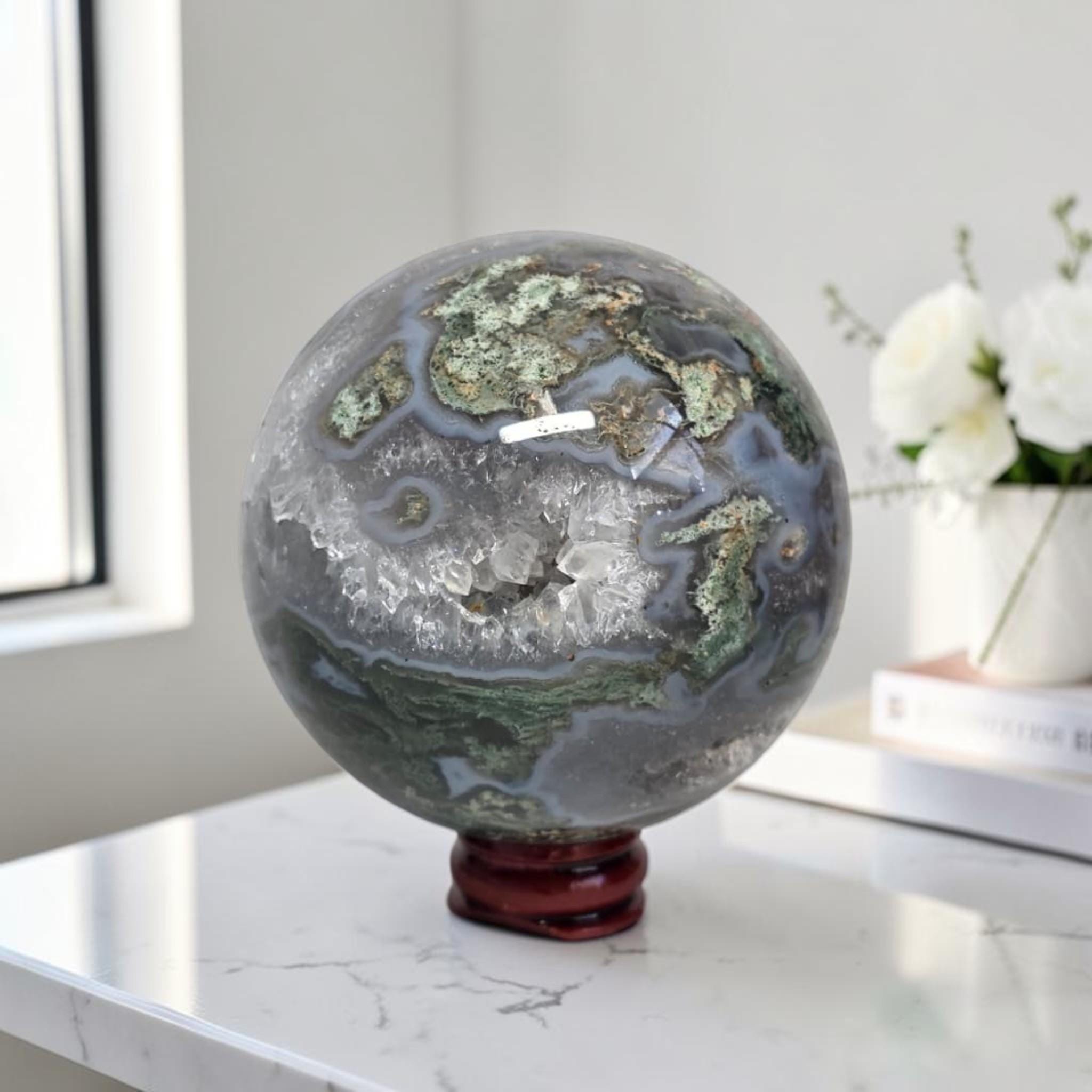 Moss agate geode sphere: dark gray-blue with bright green mossy areas and white druzy quartz