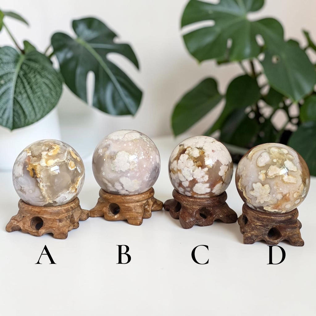 Four flower agate drusy spheres on carved wooden stands, white faces with golden patches