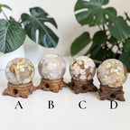 Four flower agate drusy spheres on carved wooden stands, white faces with golden patches