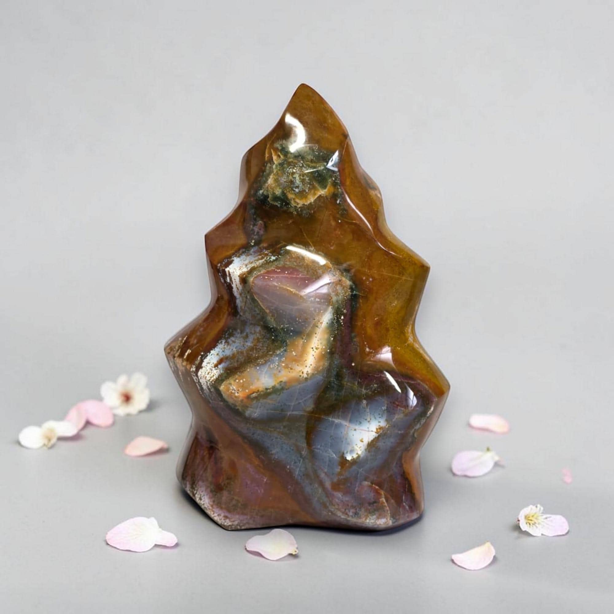 Polished flame-shaped jasper stone, golden amber with dark gray-blue and maroon flecks