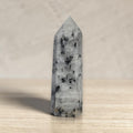 Tourmalinated quartz tower with black crystal inclusions, pointed obelisk form.