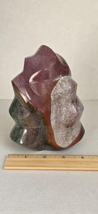 Flame-shaped jasper crystal sculpture with purple-red top and green base beside ruler
